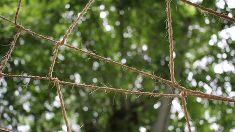 Seilnetz aus Naturfasern vor unscharfem grünem Wald.