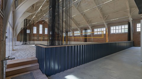 Innenraum einer Sandhalle mit Barbereich und Volleyballfeld