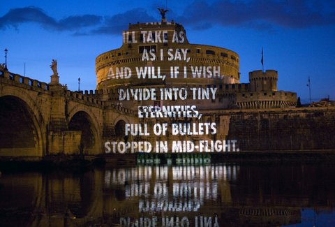 Das Castel Sant'Angelo in Rom bei Nacht mit einem auf die Fassade projizierten englischen Text und dessen Spiegelung im Wasser des Tiber.