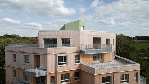 Außenansicht eines Holzgebäudes mit mehreren Balkonen, das ein zeitgenössisches architektonisches Design zeigt.