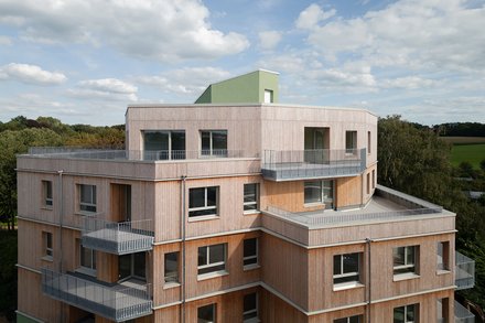 Außenansicht eines Holzgebäudes mit mehreren Balkonen, das ein zeitgenössisches architektonisches Design zeigt.