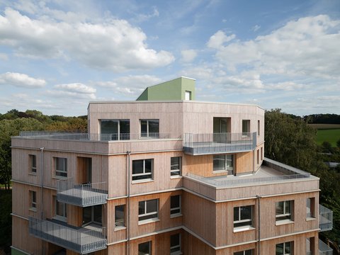Außenansicht eines Holzgebäudes mit mehreren Balkonen, das ein zeitgenössisches architektonisches Design zeigt.