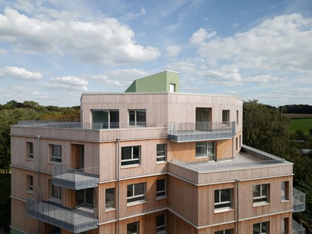 Außenansicht eines Holzgebäudes mit mehreren Balkonen, das ein zeitgenössisches architektonisches Design zeigt.