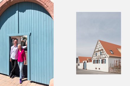 Weit geöffnete, hellblaue Torflügel in einem großen Sandsteinbogen; eine Frau und ein Mann stehen lächelnd in der geöffneten Türe und blicken in die Kamera. Kleineres Bild: Gesamtansicht eines Fachwerkhauses mit hohem Giebel und rotem Ziegeldach, davor niedrige weiße Mauer und ruhige Ortsstraße.