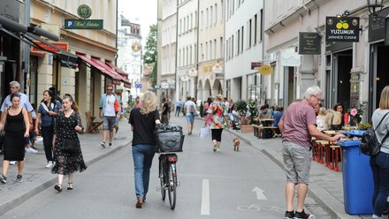 Temporär verkehrsberuhigter Straßenraum mit einer Menschengruppe, die auf der Straße spazieren geht.