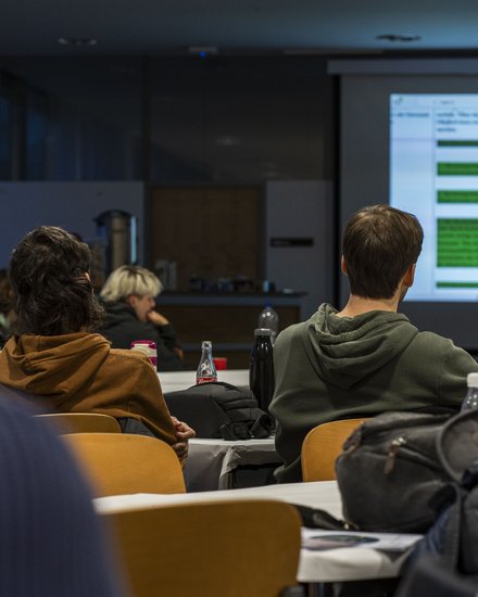 Ein Lehrsaal mit mehreren Studierenden, die auf eine Leinwand schauen