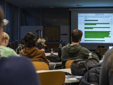 Ein Lehrsaal mit mehreren Studierenden, die auf eine Leinwand schauen