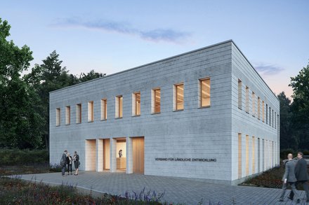 Außenansicht: Zweigeschossiger, heller Mauerwerksbau in Dämmerung; schmale Fenster mit warmem Licht, gepflasterter Vorplatz und Wildblumen; an der Fassade steht „Verband für ländliche Entwicklung“.