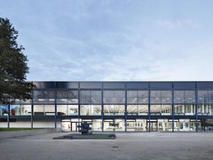 Moderne Glasfassade eines Gebäudes mit beleuchtetem Innenraum.