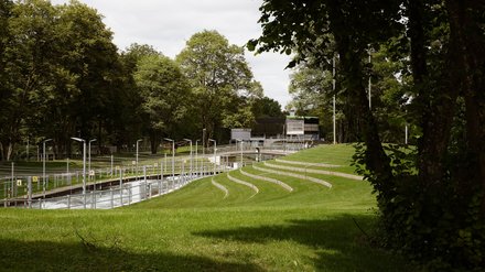 Blick über eine Parkanlage mit geschwungenen begrünten Sitzstufen am Eiskanal.