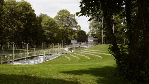 Blick über eine Parkanlage mit geschwungenen begrünten Sitzstufen am Eiskanal.