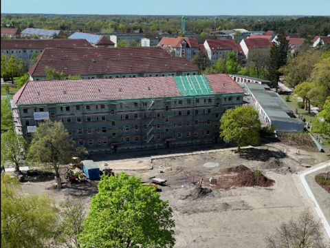 Luftaufnahme eines Modellquartiers mit saniertem Wohngebäude, neu angelegten Wegen und Grünflächen.