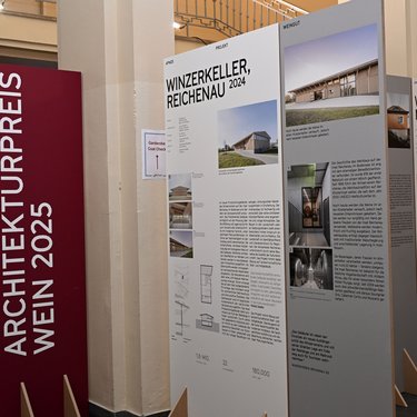 Ausstellungstafeln zu ausgezeichneten Weinbauprojekten in einem Innenraum.