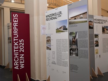 Ausstellungstafeln zu ausgezeichneten Weinbauprojekten in einem Innenraum.