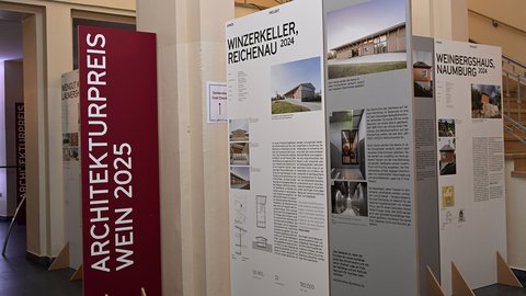 Ausstellungstafeln zu ausgezeichneten Weinbauprojekten in einem Innenraum.