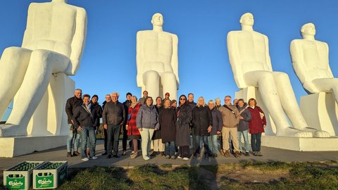 Gruppenfoto vor monumentalen weißen Skulpturen unter blauem Himmel.