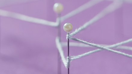 Detailaufnahme eines Netzwerk-Knotens: Weiße Perlkugel auf einer Metallstange mit verschwommenen Verbindungslinien im Hintergrund auf lila Fläche, zeigt Struktur und Verbindungen