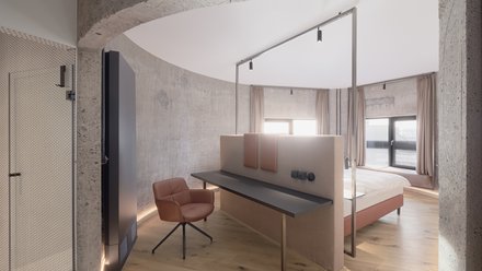 Innenansicht eines Hotelzimmers mit einem Bett und einem Schreibtisch auf der Rückseite des Bettes