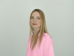 Porträt von Marta Piaseczynska-Karaivanov mit langen blonden Haaren im rosa Oberteil vor hellem Hintergrund.