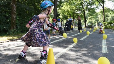Ein kleines Kind ist am Inlineskaten auf einer verkehrsberuhigten Straße.