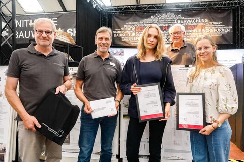 Preisträger:innen stehen nebeneinander und halten Urkunden bei einer Preisverleihung.