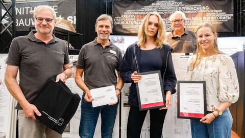 Preisträger:innen stehen nebeneinander und halten Urkunden bei einer Preisverleihung.
