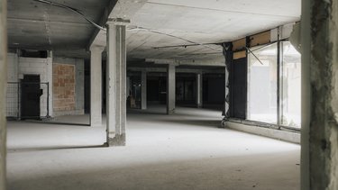 Rohbau-Innenraum eines Schulgebäudes mit Betonstützen, Decken und großflächigen Fensteröffnungen.