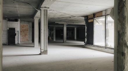 Rohbau-Innenraum eines Schulgebäudes mit Betonstützen, Decken und großflächigen Fensteröffnungen.