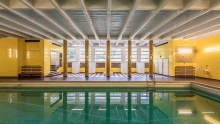 Innenraum eines historischen Hallenbads mit Schwimmbecken.