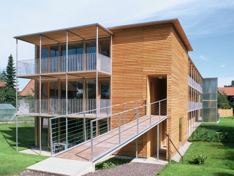 Holzfassade eines Hauses mit Balkonen und Laubengang