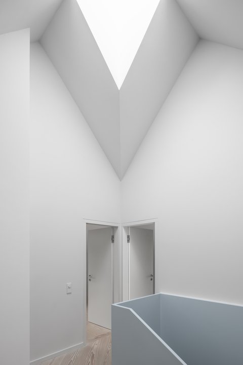 Galerie mit hoher, weißer Decke, Oberlicht und hellblauer Brüstung vor zwei geöffneten Türen.
