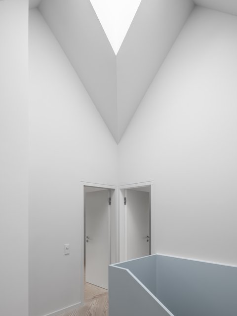 Galerie mit hoher, weißer Decke, Oberlicht und hellblauer Brüstung vor zwei geöffneten Türen.