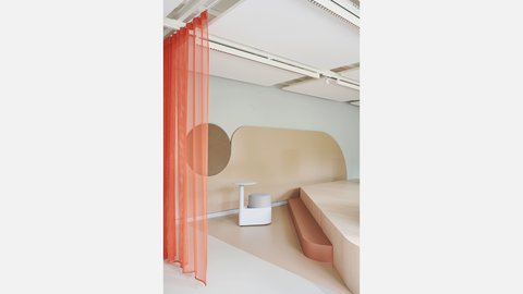 Modern gestalteter Sitzbereich mit hellem Podest, integrierter Bank und kleinem Beistelltisch. Ein halbtransparenter Vorhang und sanfte Farbtöne schaffen eine ruhige Atmosphäre.