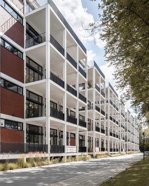 Moderner mehrstöckiger Bürokomplex mit großen Fenstern und Balkonen an einer Baumallee