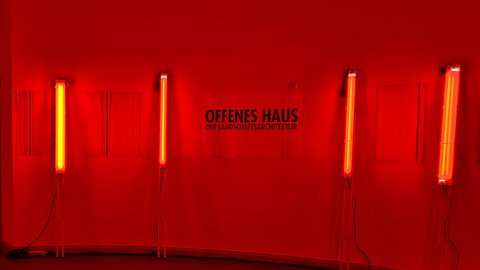 Rot beleuchteter Ausstellungsraum mit der Aufschrift „Offenes Haus der Landschaftsarchitektur“.