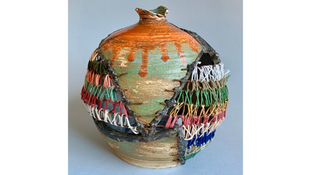 Rustikale Vase mit orangegrünem Glanz; große Risse mit Metallnähten und farbigem Garngeflecht provisorisch geschlossen.