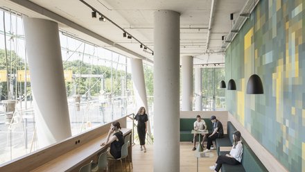 Langer Raum mit Arbeitsplätzen, Sitzbänken und Blick nach außen.