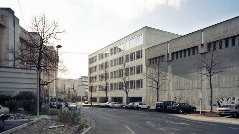 Großes, modernes Gebäude an einer Straße mit angrenzenden Wohnhäusern.