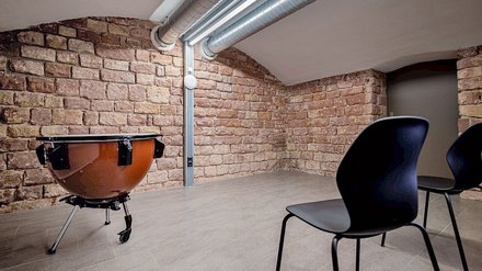 Eine Trommel vor einer Backsteinwand und zwei Stühle