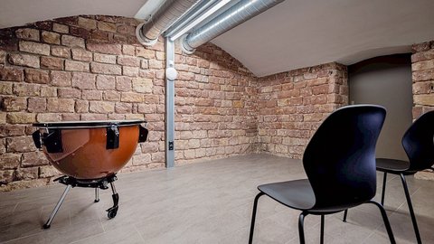 Eine Trommel vor einer Backsteinwand und zwei Stühle