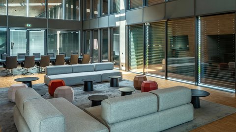 Stilvoller Lounge- und Konferenzbereich mit Holzdecke und Glasfassade