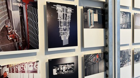 Mehrere Fotografien hängen einzeln mit Abstand an einer Wand. Zu sehen sind historische und moderne Technikräume: Rechenzentren, Schaltschränke, Kabelbündel und alte Computersysteme. Das Bild zeigt eine visuelle Erzählung der Entwicklung von Rechen- und Speichertechnologien. Es verdeutlicht die materielle Seite digitaler Systeme.