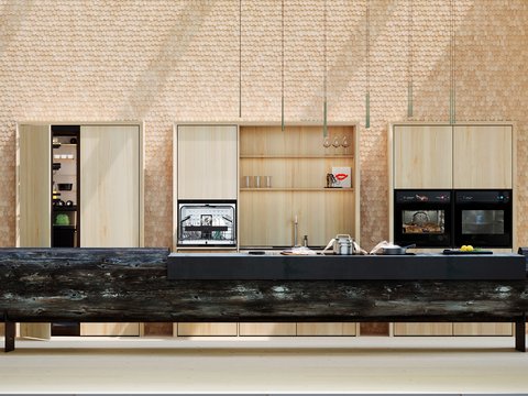„Eine moderne Designerküche mit einer monumentalen Kücheninsel aus einem Baumstamm vor einer Schindelwand mit integrierten Einbaugeräten.“