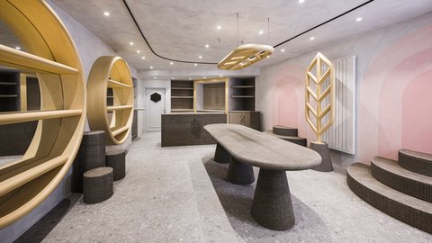 Modern gestalteter Arbeits- und Empfangsbereich mit organisch geformtem Tisch, runden Regalen und dekorativen Holzelementen