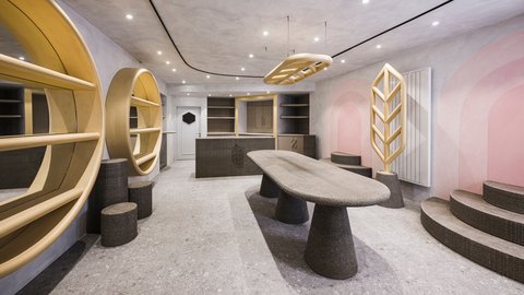 Modern gestalteter Arbeits- und Empfangsbereich mit organisch geformtem Tisch, runden Regalen und dekorativen Holzelementen