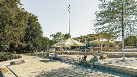 Öffentlicher Platz mit Sitzstufen und Café, Menschen sitzen, stehen und fahren Fahrrad.