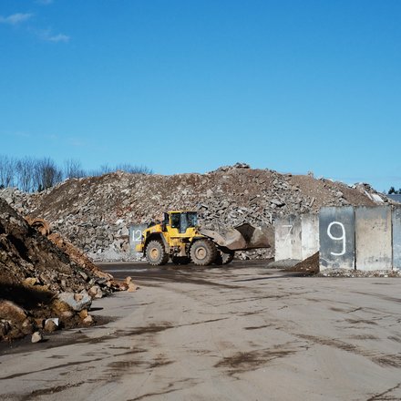 Gelber Radlader auf einem Schutt- und Recyclinggelände.