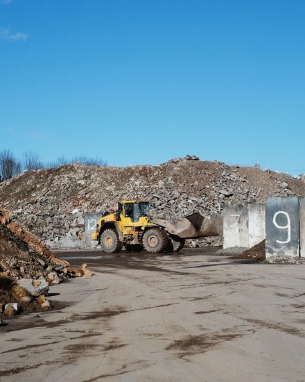 Gelber Radlader auf einem Schutt- und Recyclinggelände.