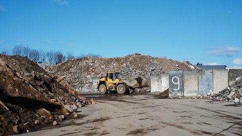 Gelber Radlader auf einem Schutt- und Recyclinggelände.