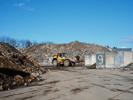 Gelber Radlader auf einem Schutt- und Recyclinggelände.